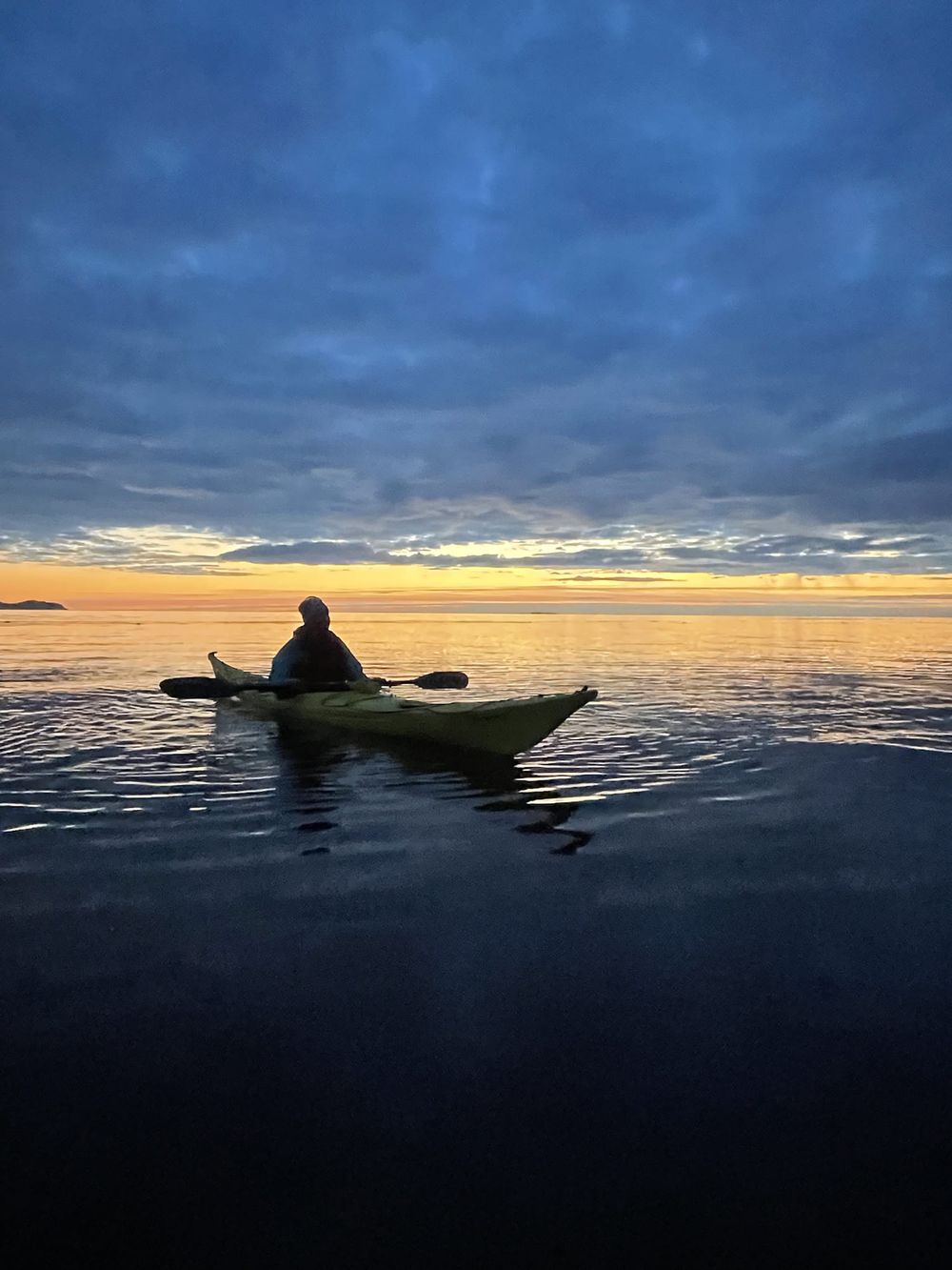 Padler i silhuett mot gyllen solnedgang